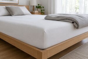 木のベッドの厚いマットレスにかぶせた白いボックスシーツ